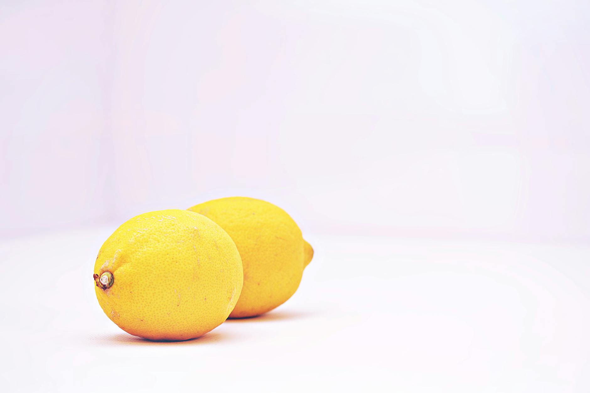 Two vibrant lemons against a minimalistic white background, symbolizing the precision and simplicity of lemon clitoral vibrators