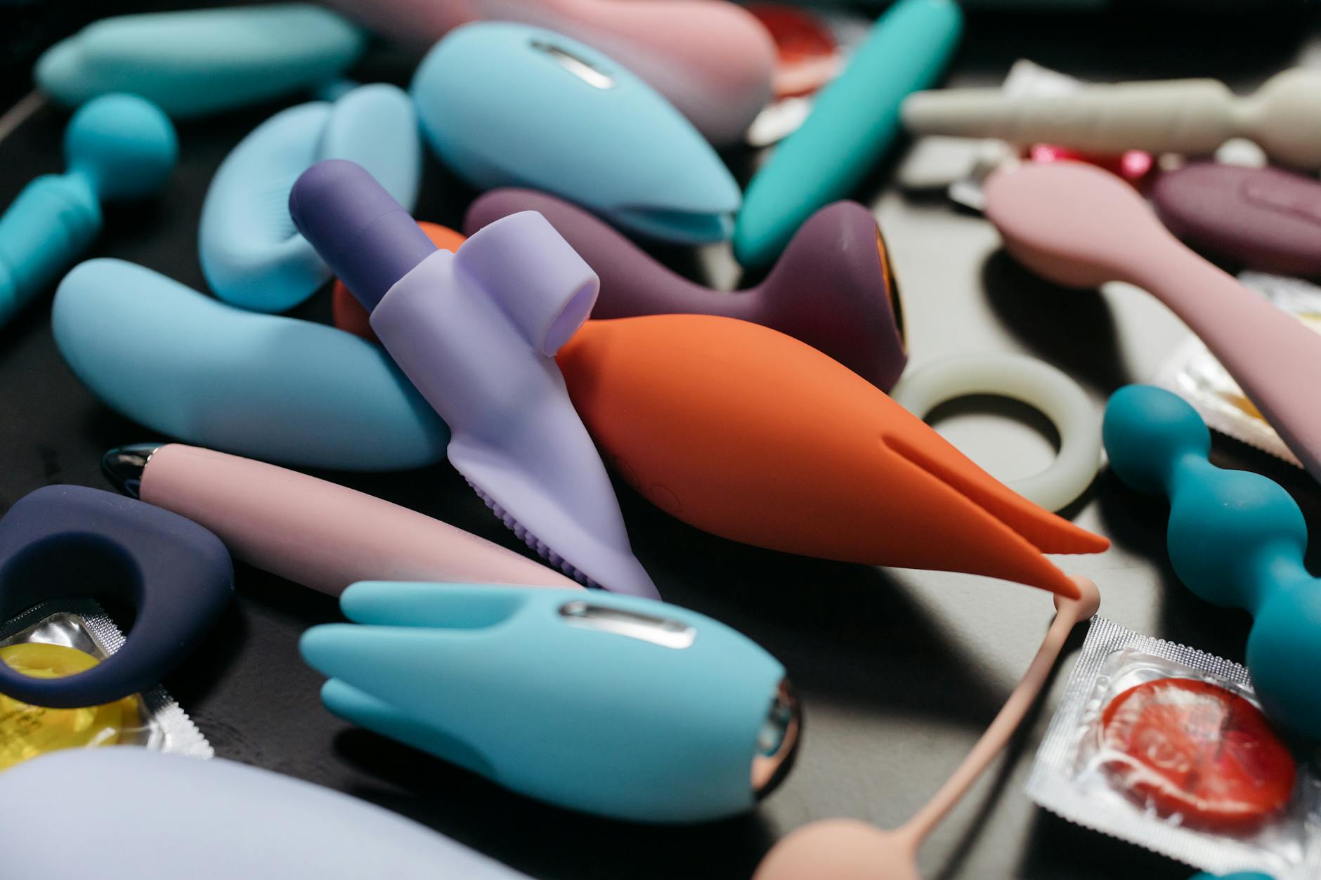 A blue silicone vibrator held gently in hand against a purple background