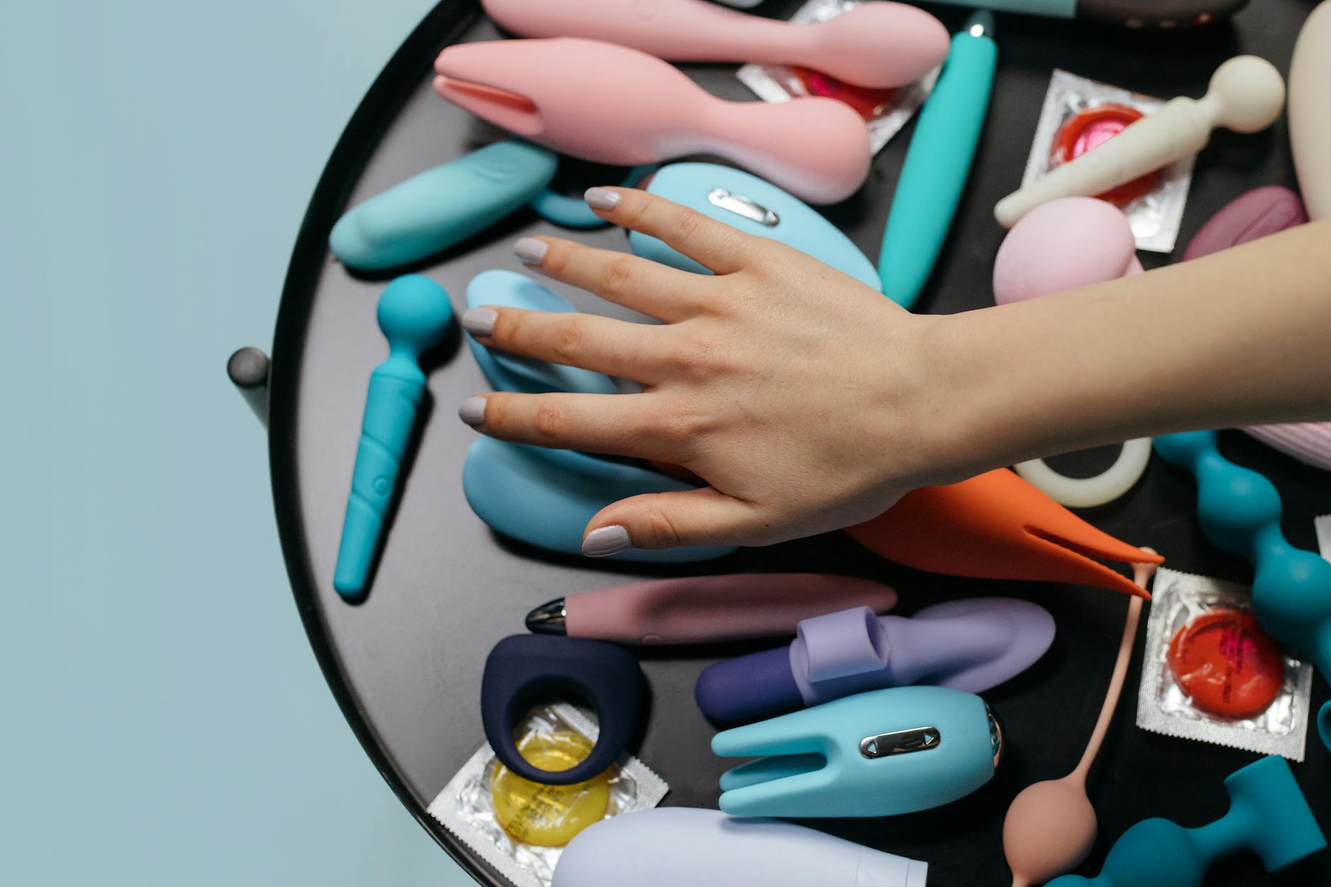 A close-up of a hand holding an orange vibrator against a minimalistic purple backdrop, showcasing modern sensuality.