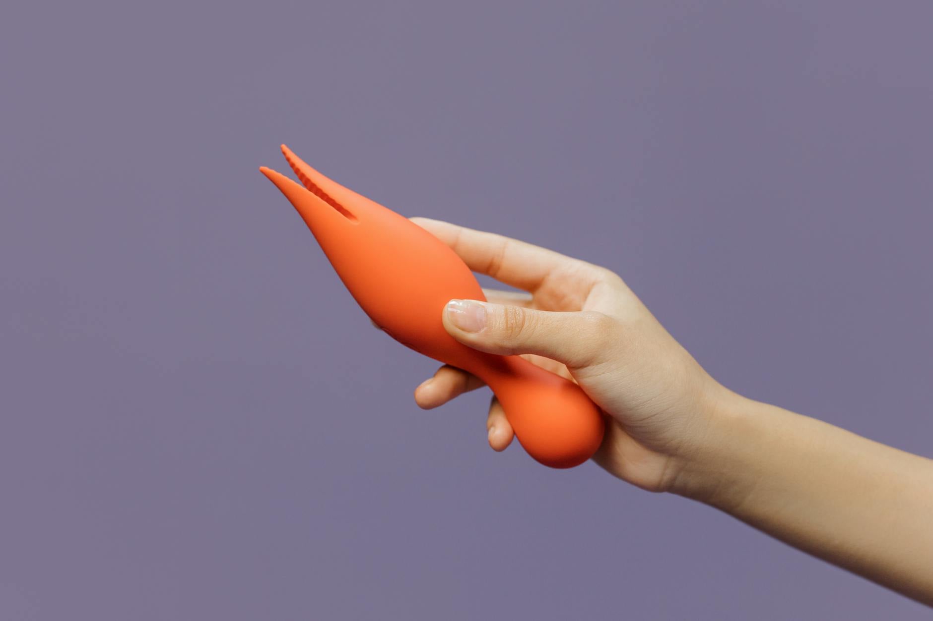 A hand holding a lemon-colored vibrator against a soft purple background, symbolizing gentle pleasure without pressure