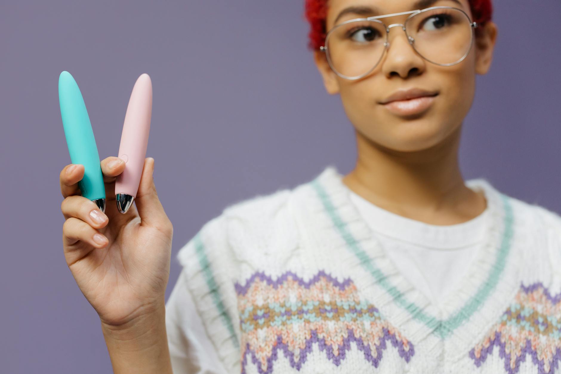 Close-up of hands holding a blue personal massager against a knitted sweater, representing intimate partner connection.