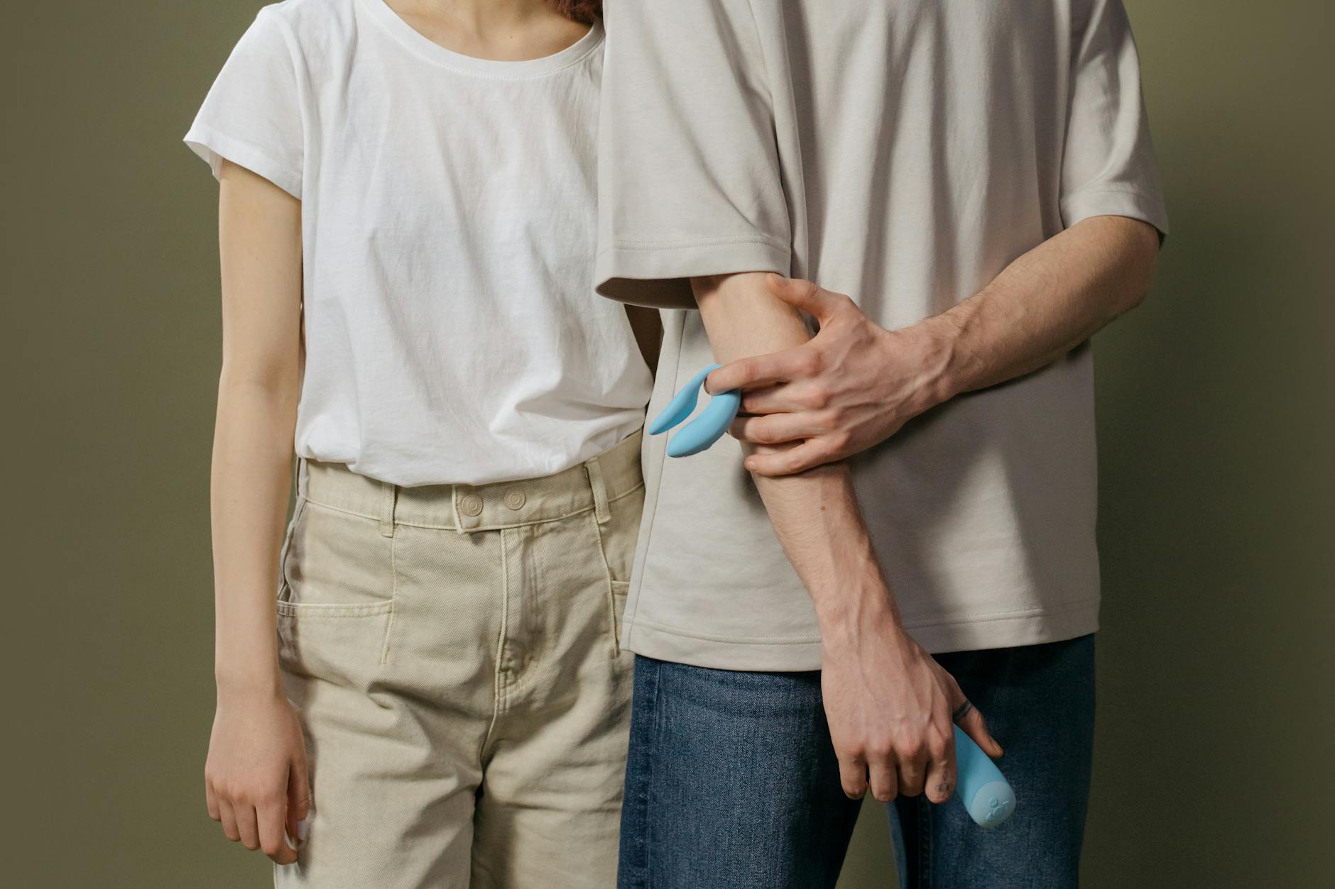A couple holding a blue vibrator together, symbolizing modern intimacy and renewed connection.